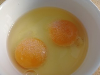 芹菜叶炒鸡蛋,鸡蛋打入碗里，加半小勺盐入味。