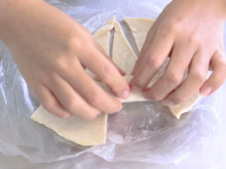 手抓饼的多样吃法,用手抓饼把香肠卷起来，从三角形大的一头开始卷，卷好后放在烤盘里，烤盘里提前铺一层油纸。