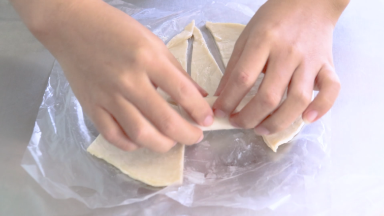 手抓饼的多样吃法,用手抓饼把香肠卷起来，从三角形大的一头开始卷，卷好后放在烤盘里，烤盘里提前铺一层油纸。