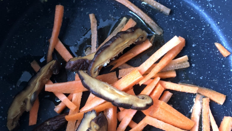 黄花菜炒肉丝,下入香菇丝和胡萝卜丝。