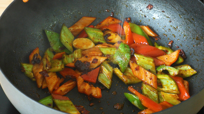 爆香味辣：农家小炒肉,另起锅烧油，加入蒜瓣和豆瓣酱，再加入切好的青、红椒；
