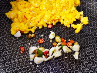 芹菜叶炒鸡蛋,然后将炒熟的鸡蛋推向锅边，将蒜和青红椒加入锅中炒香