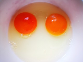 芹菜叶炒鸡蛋,碗中打入两个鸡蛋