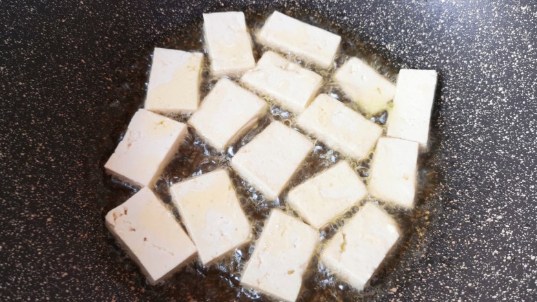 雪菜豆腐,炒锅内倒多一些食用油烧热，码入豆腐片。