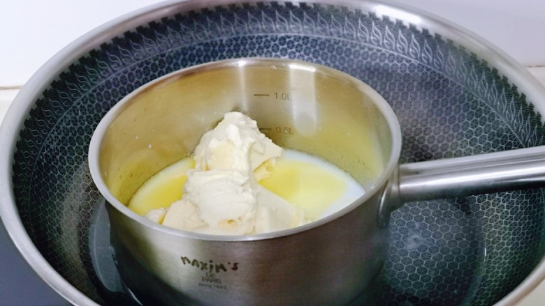 半熟芝士蛋糕,<a style='color:red;display:inline-block;' href='/shicai/ 48598'>奶油奶酪</a>与牛奶放入耐高温的器具中，隔水融化，一边用手动打蛋器搅拌。
