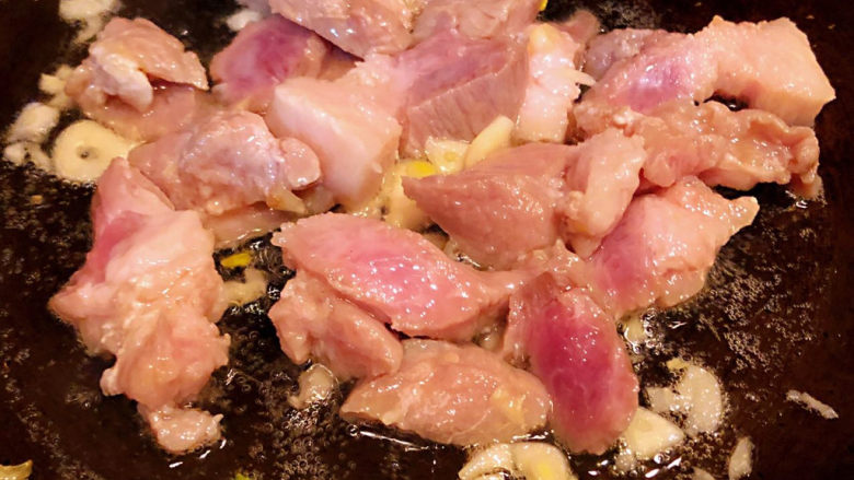干锅千页豆腐,锅中倒入底油加热放入蒜粒爆香再放入猪肉炒至变色