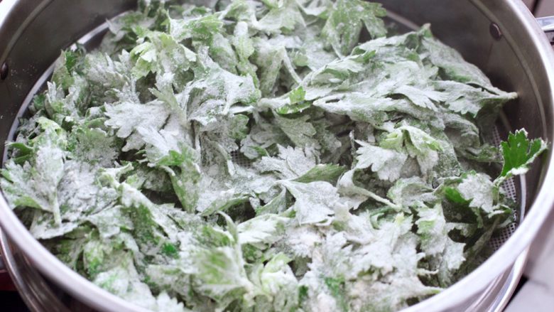 粉蒸芹菜叶,锅中倒入适量的清水烧开后，把搅拌均匀的芹菜叶放入锅中。