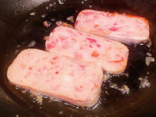 紫米饭团,锅中倒入少许底油加热放入午餐肉片煎至两面熟透
