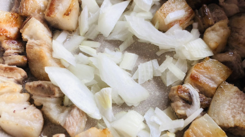 梅干菜烧肉,煎制五花肉上色后倒入切好的洋葱炒出香味。