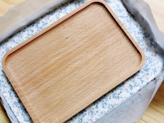 芝麻花生糖,在上面盖一层油纸，用一个平的板，将糖表面压平。