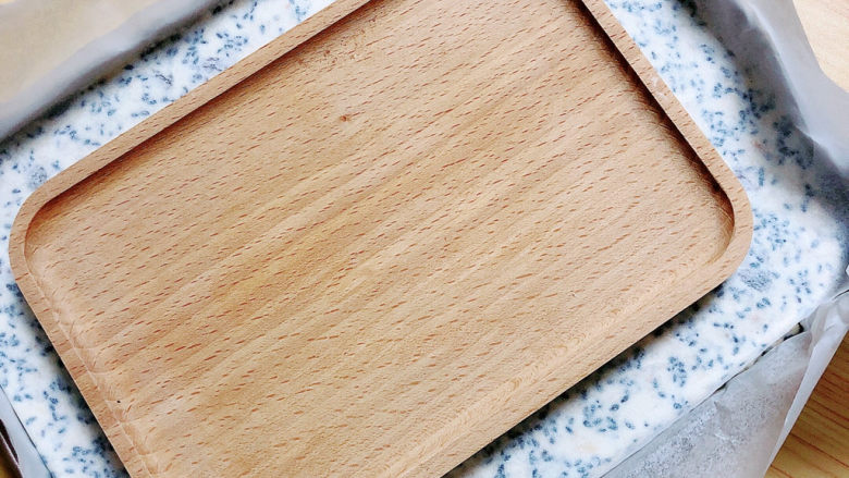 芝麻花生糖,在上面盖一层油纸，用一个平的板，将糖表面压平。