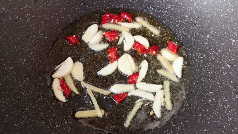 酸菜肥牛,炒锅内倒适量的食用油烧热，下入姜丝蒜片和干红辣椒炒香。
