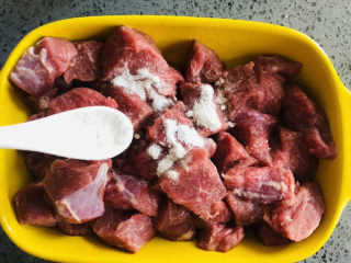 简单美味的杏鲍菇牛肉粒,牛肉切块，加入淀粉，盐，图中所示是一茶匙。