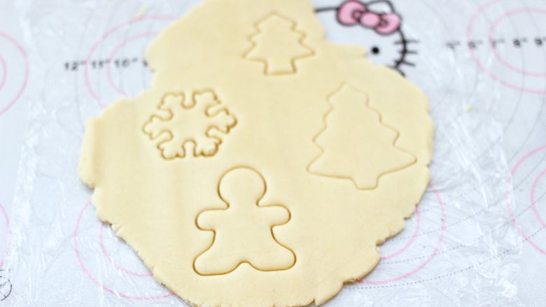 圣诞双色饼干,硅胶垫底下铺上一层保鲜膜，把取出的面团擀薄，用模具压出喜欢的形状。