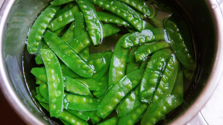 清炒甜豆,锅中水沸加一克盐，甜豌豆入锅焯烫至变为翠绿色，三十秒，捞出过冷水