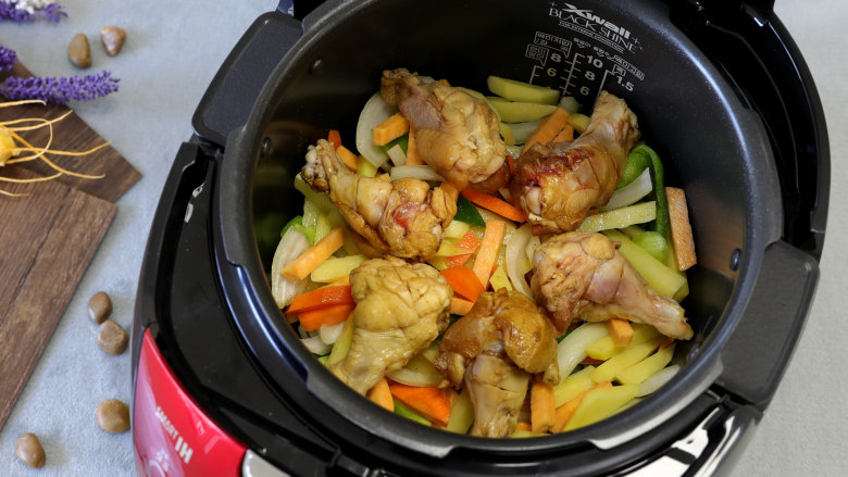 三汁闷锅，满满的都是肉香,将蔬菜倒入电饭煲中，再将腌制好的鸡腿铺在蔬菜上面