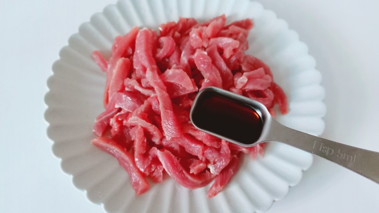 尖椒牛柳,牛肉放在盘子里加上生抽一勺。