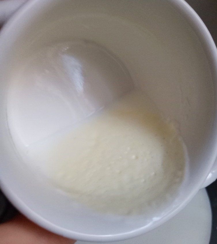 红豆双皮奶,这时候牛奶表面也结了奶皮。从边缘用牙签轻轻划个口，把牛奶倒在一个大盆里。最好留点牛奶，不要都倒出来，如图
