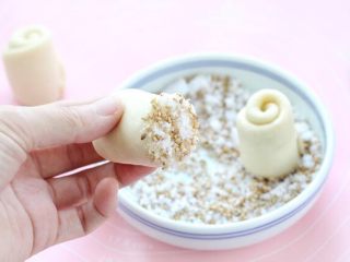 蜂蜜小面包,十克细砂糖中加入适量芝麻拌匀，将面胚切口的那面蘸上白糖芝麻。