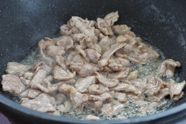 辣椒炒千张,锅中倒入食用油烧热，将腌制好的肉片放进去炒至发白断生状态盛出。