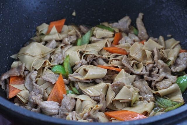 辣椒炒千张,再将肉片放入锅中，与干豆腐混合翻炒均匀。