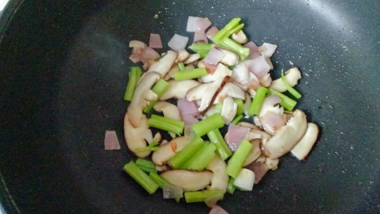 鸡蛋炒乌冬面,锅中加入适量花生油烧热，放入洋爆香，加入香菇和芹菜翻炒1分钟
