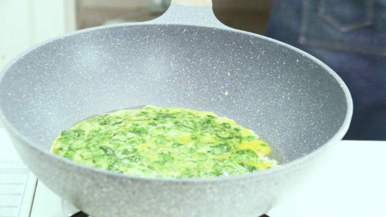 芹菜叶炒鸡蛋,把蛋液倒入锅中，稍后轻轻晃动锅子