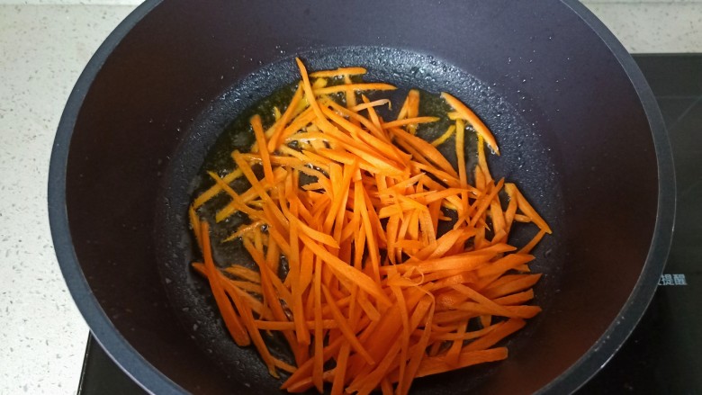 青椒炒千张,锅里放适量的食用油，油热放入胡萝卜丝煸炒。
