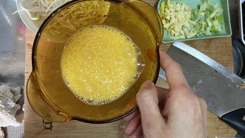 鸡蛋炒乌冬面➕鸡蛋腊肠豆芽炒乌冬面,鸡蛋打入碗中，搅拌成均匀蛋液