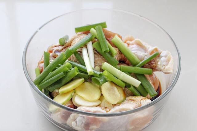 电饭锅焖鸡腿,将调好的酱汁倒入鸡腿中，再放入葱段、姜片和蒜片。