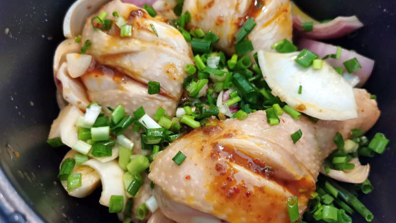 电饭锅焖鸡腿,洋葱与鸡腿先放进来，表面撒上葱花