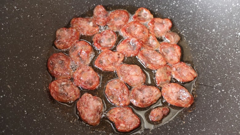 萝卜干炒肉,炒锅内倒适量的食用油烧热，下入腊肠煎至边缘卷曲，盛出备用。