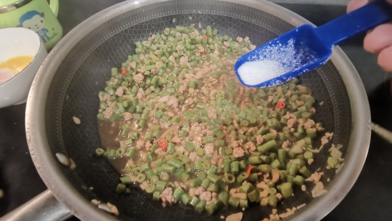 肉末豇豆,加入水在锅中炖一会儿，加入盐。