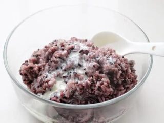 紫米饭团,将煮好的紫米饭盛入容器中晾至不烫手的状态，加一汤匙炼乳混合拌匀。