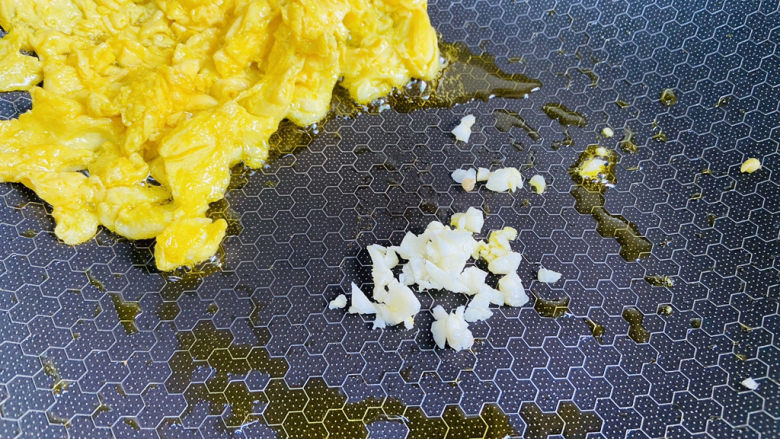 尖椒炒鸡蛋,用锅铲拔到锅边，放入蒜末炒香