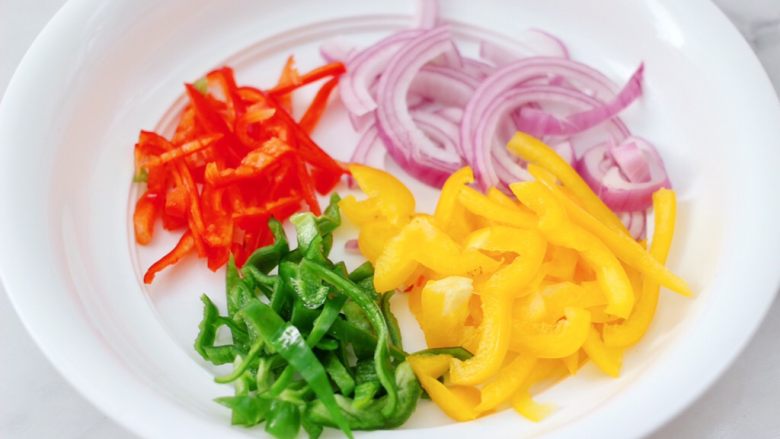 柠香彩蔬鸡胸肉,把切丝的青，红、黄辣椒和洋葱丝放入容器里。