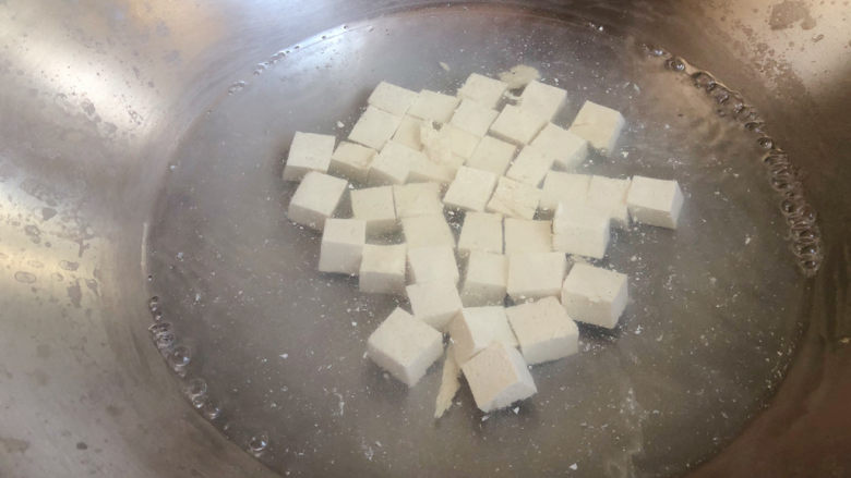 白玉菇豆腐汤,豆腐丁入锅中焯烫半分钟，捞出沥干。