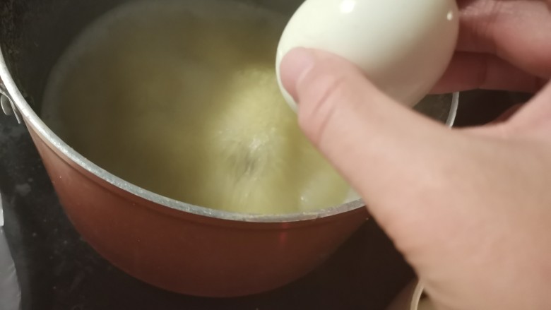 鸡蛋小米粥,煮沸的锅中放入鸡蛋。