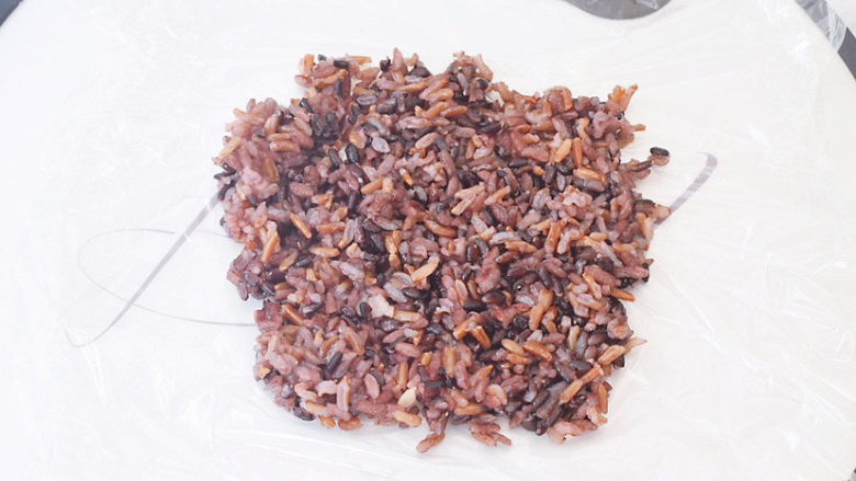 紫米饭团,煮熟后取一张保鲜膜，把米饭均匀的铺在上面