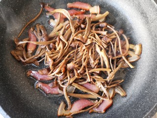 干锅茶树菇,加入茶树菇一起翻炒，让茶树菇沾满腊肉的香气后盛出。