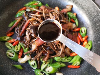 干锅茶树菇,将腊肉和茶树菇回锅，加1勺味极鲜酱油和1勺蚝油。