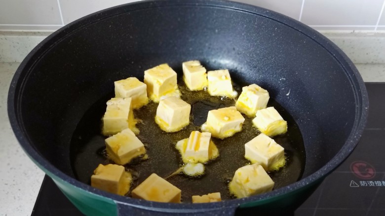 豆腐炒鸡蛋,锅里放适量的油，把豆腐块一个个码入，开中小火慢慢煎。
