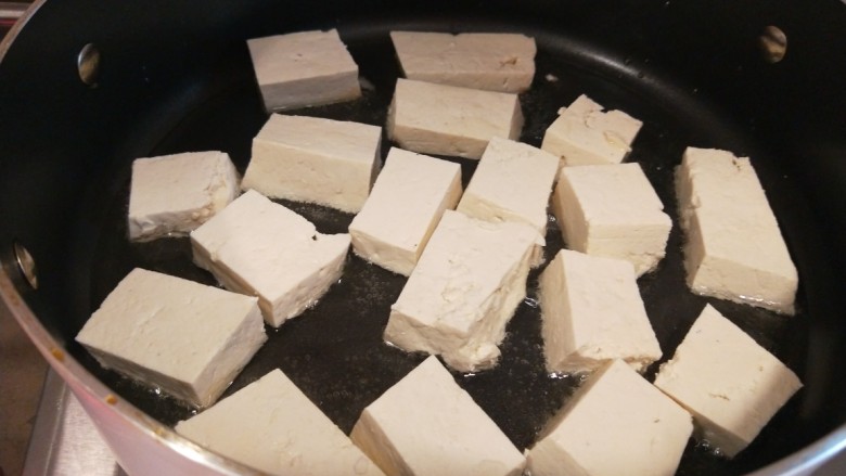 红烧米豆腐,平底锅烧热加入适量油放入豆腐。