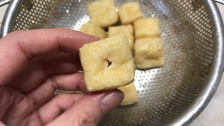 白菜炒豆腐,用筷子在油豆腐一边戳一个孔。
