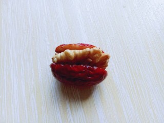 枣夹核桃,取一颗红枣，将核桃塞入红枣中。如图