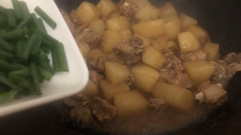 红烧土豆排骨,煮到快收汁下葱叶翻炒均匀即可