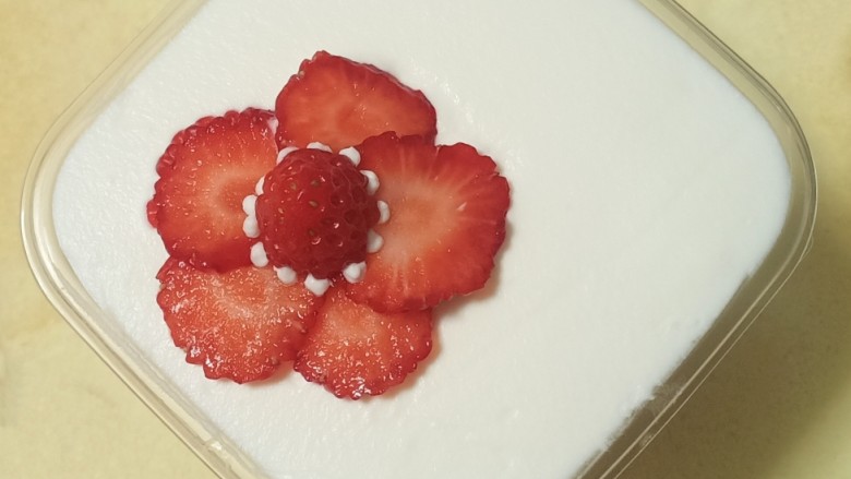 送你一朵小红花,最上面一定要用淡奶油铺，用刮刀把表面抹平。最后再放上圆形的草莓片。中间用奶油挤出小球做装饰。这道甜品就完成了。