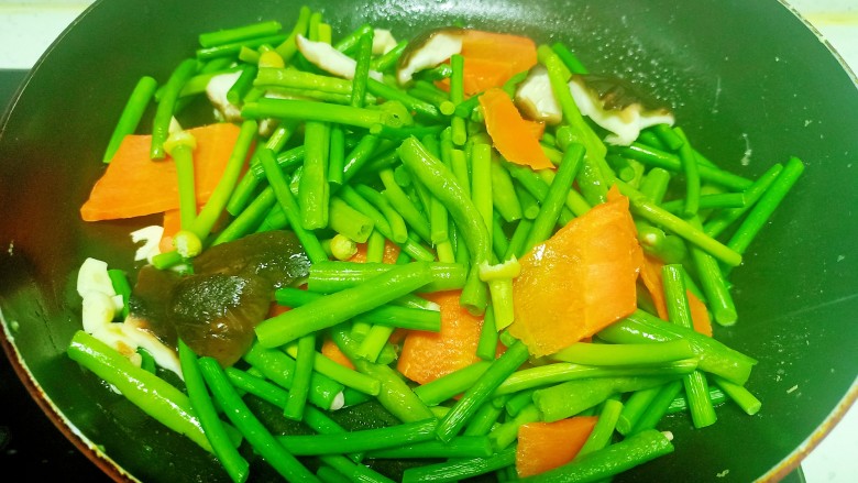 蒜台、豆角 、胡萝卜、 香菇炒鸡蛋,锅中放入少量油， 放入蒜拌炒香， 放入焯过水的蔬菜 
