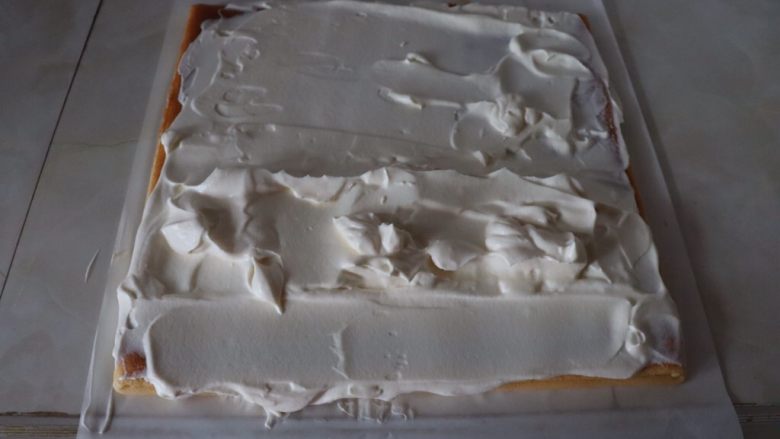 草莓香草奶油蛋糕卷,蛋糕片距离前端3cm多抹一些奶油，抹成小山丘，蛋糕片前端与尾部奶油抹平^o^
