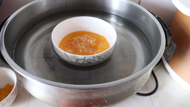 小熊维尼芒果慕斯蛋糕,泡软的吉利丁片从冷水中取出，放入到芒果汁里，把碗放入锅中，隔水加热^o^